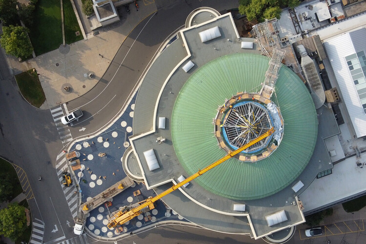 Construction crews work to lift a piece of the new roof onto Convocation Hall.