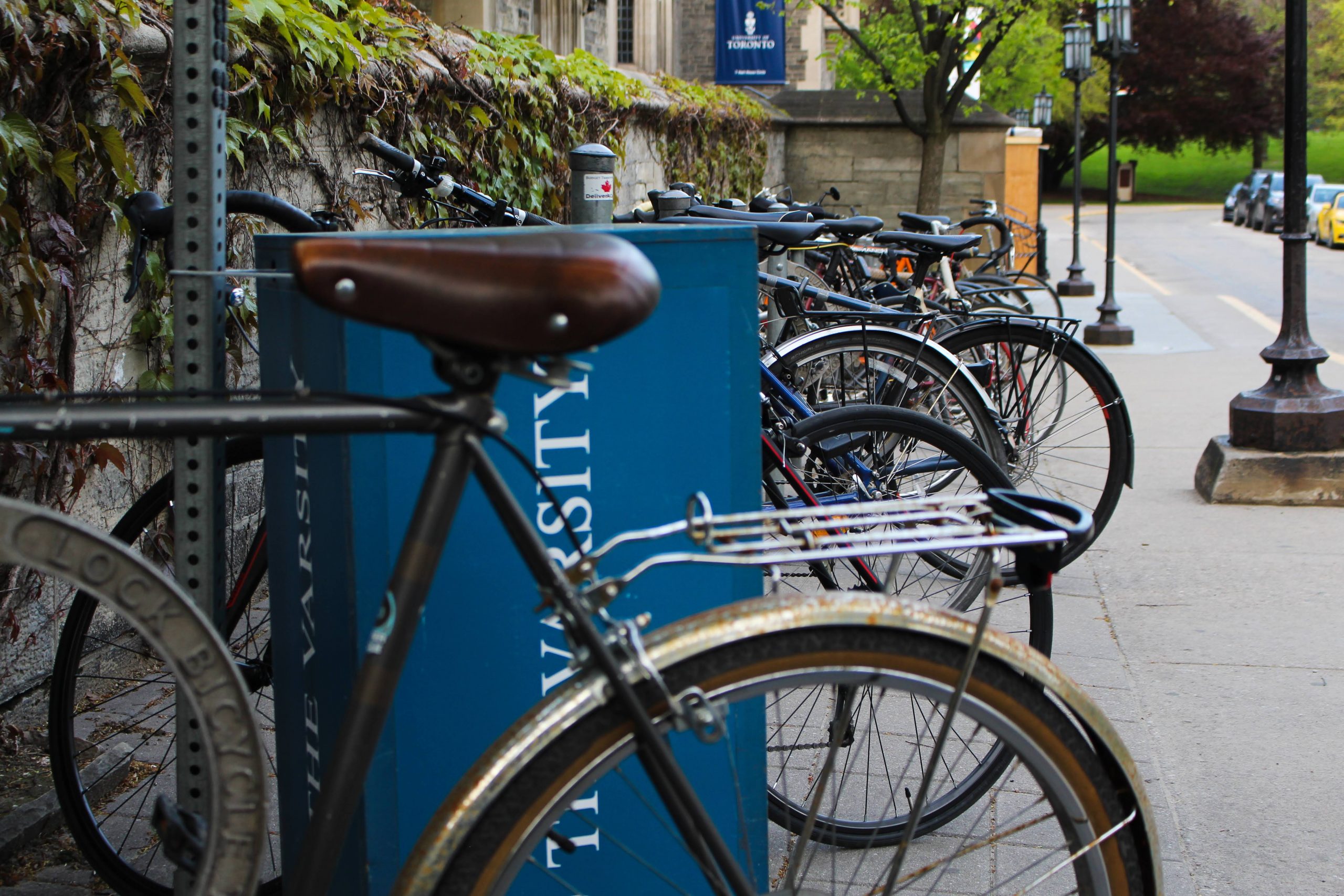 A row of bikes parked in a bike rack outside of Hart House