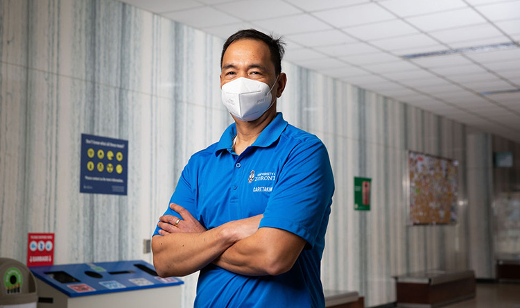 A caretaker wearing a mask stands with their arms crossed.