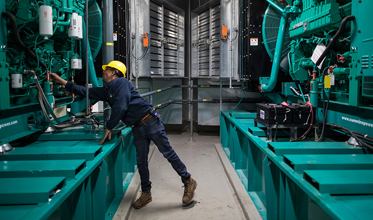 An employee inspects a generator on campus.