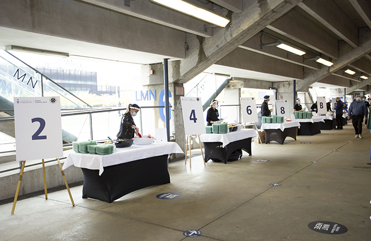 Catering team members wearing masks and physically distanced, ready to serve food.