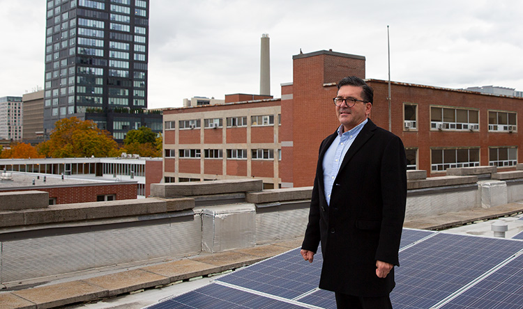 Vic Cassano stands near solar panels on the roof of the Exam Centre.