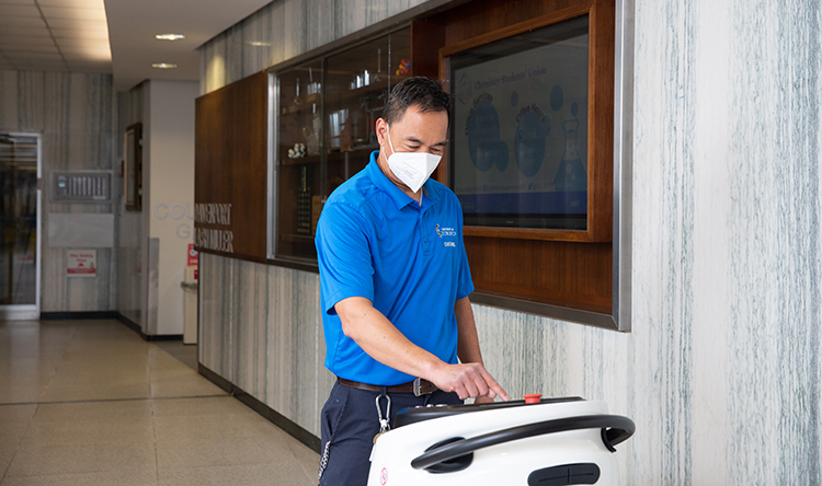 A caretaker uses a cleaning robot at Lash Miller Chemical Laboratories.