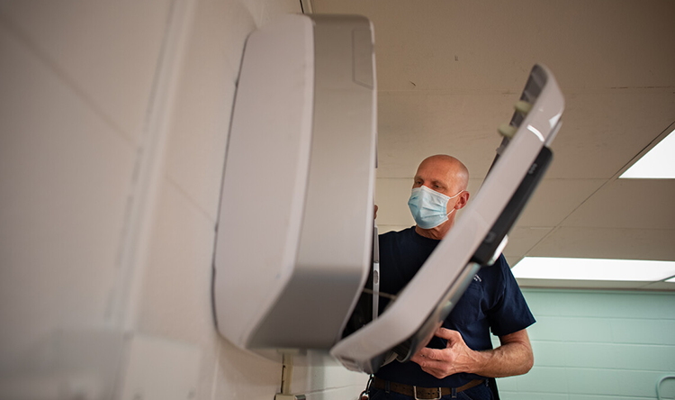 A technician checks the operation of the HEPA air purifier in a classroom.