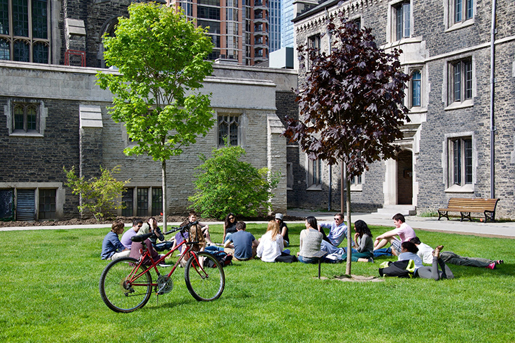 A group of students gathered outside of Burwash Hall at Victoria College.