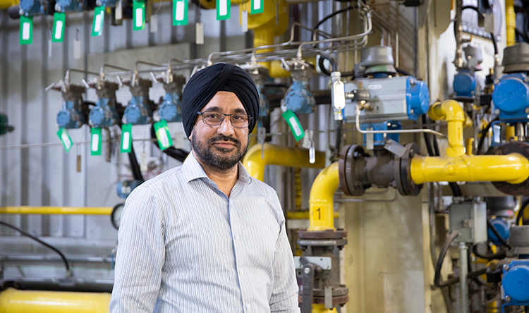 Gurmel Multani stands in front of pipes and knobs at the Central Steam Plant.