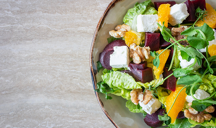 A bowl of salad with beet, feta, and orange pieces.