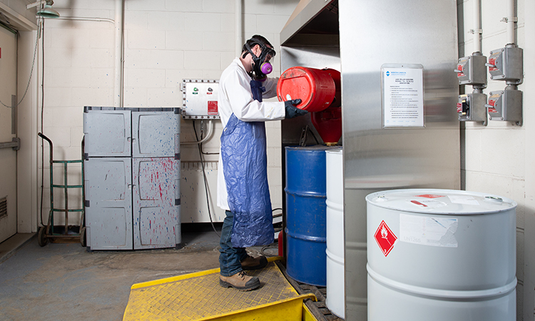 A member of the Environmental Protection Services team prepares chemicals for disposal.
